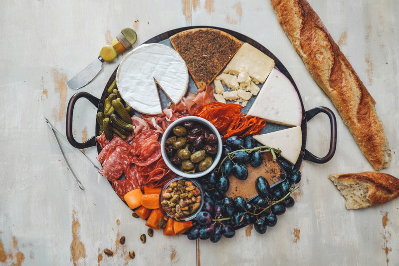 Plateau de présentation garni de charcuterie, fromages et raisins sur une table de buffet